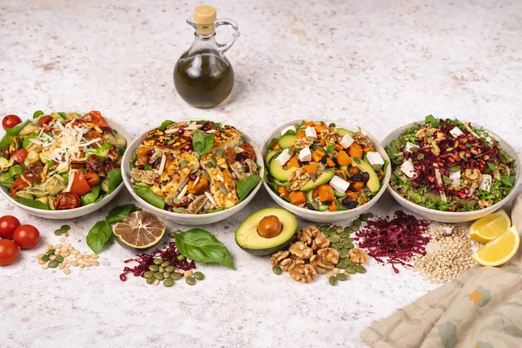 Four colorful Eatjoy salad bowls with fresh vegetables, avocado, cheese and seeds